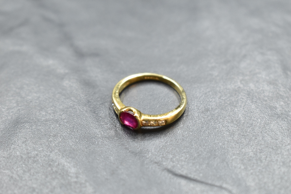 A ruby and diamond ring having a central oval ruby having diamond set shoulders on an 18ct gold