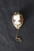 A conch cameo brooch depicting a Grecian maiden in profile, in a yellow metal decorative mount,