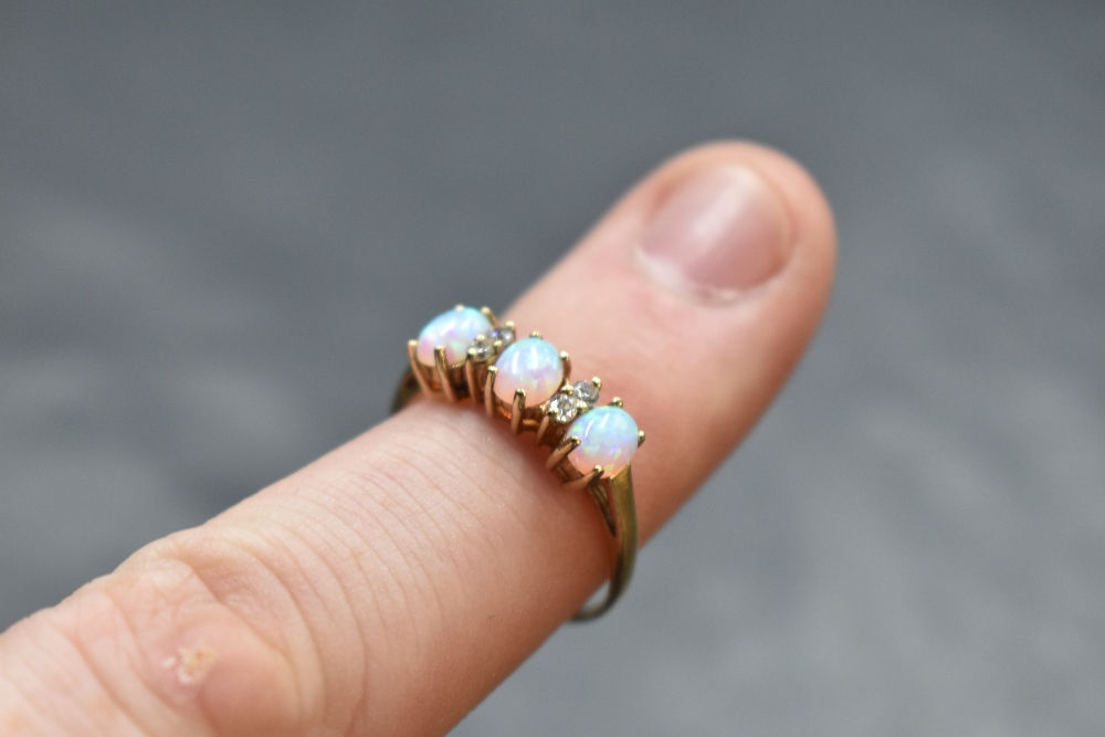 A 9ct gold opal and cubic zirconium ring, the oval opal cabochons interspersed by small brilliant- - Image 2 of 2