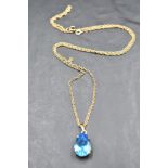 A 9ct gold pendant and chain having a pear drop shaped blue topaz in a claw set mount on a fine rope