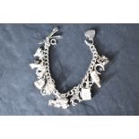 A silver charm bracelet having sixteen white metal charms, most stamped silver, including vespa,