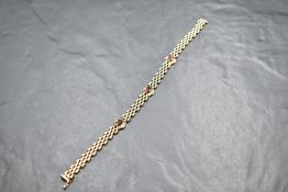 A 9ct gold brick link bracelet having three garnet set panels and a slide clasp, approx 190mm & 9g