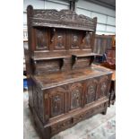 A period oak cabinet having extensively carved ecclesiastical panels with adapted shelves to rear