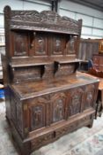 A period oak cabinet having extensively carved ecclesiastical panels with adapted shelves to rear