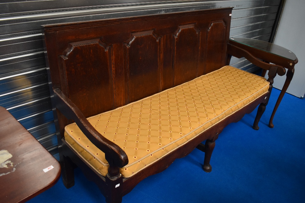 An 18th Century and later oak settle having panelled back and webbed seat with later bespoke seat
