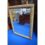 A gilt frame over mantel mirror of large proportions with vine decoration