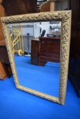 A gilt frame over mantel mirror of large proportions with vine decoration