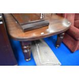 A Victorian mahogany wind out dining table on heavy fluted legs with two additional leaves