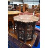 An Eastern style occasional table with carved decoration to top and to folding frame