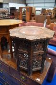 An Eastern style occasional table with carved decoration to top and to folding frame