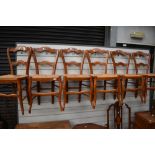 A set of six stained frame kitchen chairs having shaped rail backs and rush seats