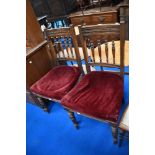 A pair of Victorian oak dining chairs having spindle backs and over stuffed seats