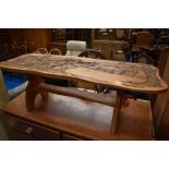 A traditional golden oak coffee table having carved ploughing decoration, width approx. 111cm