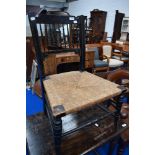 A Victorian ebonised chair having spindle back and rush seat with turned legs and supports