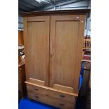 A Victorian stripped pine wardrobe on double drawer base