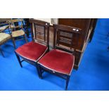 A pair of Victorian mahogany dining chairs having red dralon drop in seats