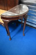 A reproduction demi lune hall table with glass top protector