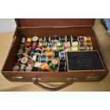 A suitcase containing vintage and antique bobbins of thread.