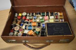 A suitcase containing vintage and antique bobbins of thread.