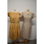 Two vintage dresses, including 1950s caramel pleated dress with white polka dots and 1960s wiggle