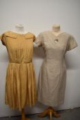 Two vintage dresses, including 1950s caramel pleated dress with white polka dots and 1960s wiggle