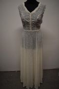 A stunning semi sheer late 1930s/ early 1940s white evening gown, having side metal zip, scalloped