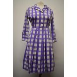 A late 1950s/ early 1960s cotton day dress having bold purple checked pattern, side metal zip, 3/4