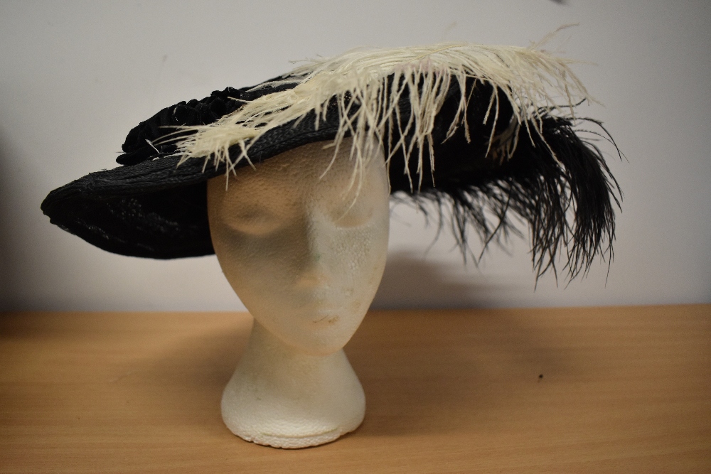 An Edwardian black straw hat, having feathers and velvet trim to brim and two hat pins.