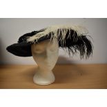 An Edwardian black straw hat, having feathers and velvet trim to brim and two hat pins.