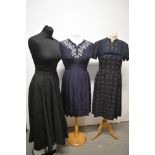 Two 1950s day dresses, including grey wool with blue and pink pattern and navy blue with pleated
