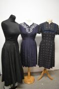 Two 1950s day dresses, including grey wool with blue and pink pattern and navy blue with pleated
