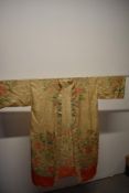 An early 20th century cream silk kimono dressing gown, having traditional scenes of buildings,