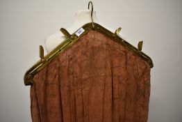 A vintage brown cotton clothes bag with brass fittings.