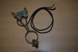 A Victorian brass skirt lifter on lanyard with butterfly detailing.