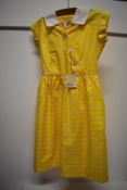 A 1950s dead stock children's yellow cotton day dress with original tag, having striped pattern in