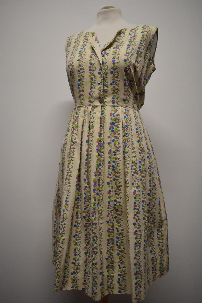 A 1950s medium weight floral cotton day dress having pleated skirt, button front and side press stud