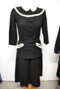 A 1940s black wool two piece outfit, comprising; belted top with pique collar and braid detailing to