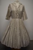 A 1950s cotton shirt waister with full pleated skirt, having taupe pattern on cream ground,