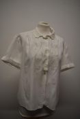 A white 1950s blouse having machine embroidered floral decoration, shaped collar, buttons to front