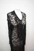 A black lace 1930s dress, having full length sleeves gathering into a pointed cuff and sash detail
