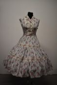 A late 1940s/ early 1950s cotton day dress, having rose pattern in pink and grey on white ground