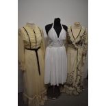 A trio of 1960s and 1970s dresses, including cream maxi dress with ruffled edge and white 1950s