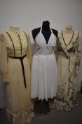 A trio of 1960s and 1970s dresses, including cream maxi dress with ruffled edge and white 1950s