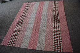 A large 19th century strippy patchwork quilt in pink and purple sprigged cottons, amongst two