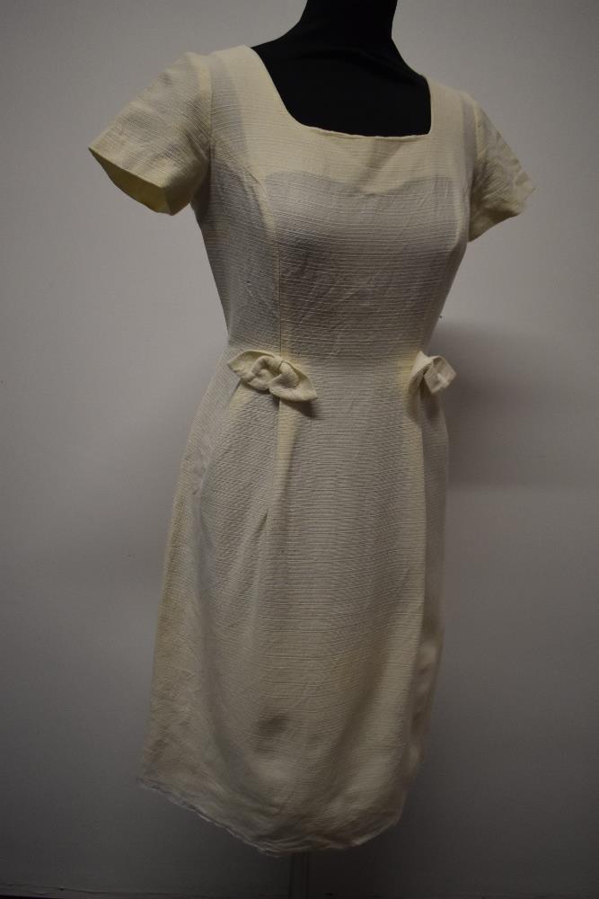 A late 1950s cream textured wiggle dress (wool blend or similar) having scoop neckline bows to hip