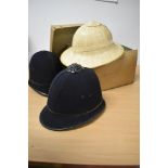Two vintage police helmets and a bamboo hat.