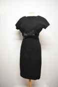 A simple, yet highly effective 1950s black wool wiggle dress, with satin bow to front which