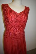 A 1950s 'Suzanne, Bradford' red organdie evening dress, having full concertina pleated skirt with