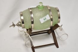A frosted green glass spirit barrel decanter and four drinking glasses, set upon a wooden stand,