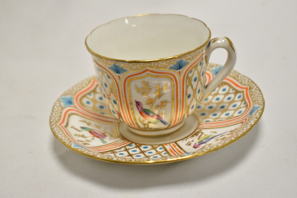 A mid-19th Century porcelain teacup and saucer, decorated with vignettes of exotic birds, the saucer